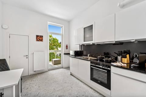 Die helle Küche ist modern ausgestattet, bietet viel Arbeitsfläche und Zugang zum Balkon für entspannte Momente im Freien.