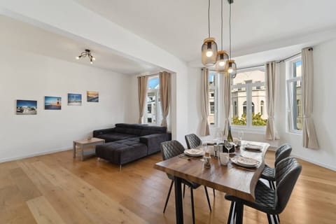 Das offene Wohn- und Esszimmer beeindruckt mit großen Fenstern, stilvollen Essbereich und gemütlicher Sofaecke für entspannte Stunden.