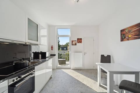 Die geräumige Küche überzeugt mit moderner Ausstattung, einem kleinen Essbereich und direktem Zugang zum Balkon.