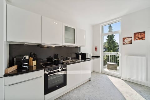 Die helle, moderne Küche ist mit hochwertigen Geräten, viel Arbeitsfläche und direktem Zugang zum Balkon ausgestattet.