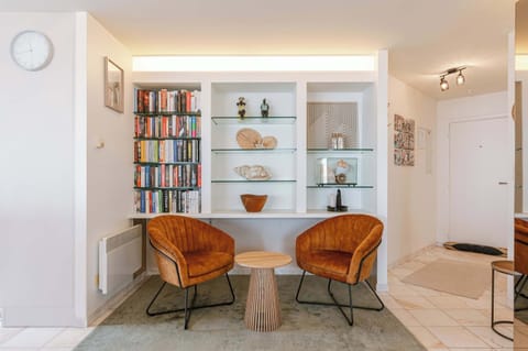 Cozy reading nook with stylish seating. Features a curated bookshelf, elegant decor, and warm-toned chairs for a relaxing atmosphere.