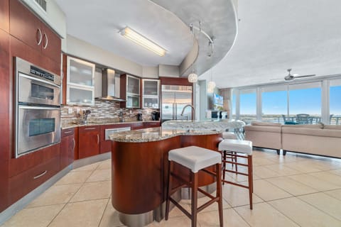 Sleek and sophisticated kitchen featuring a striking island with a stone countertop and comfortable bar stools.