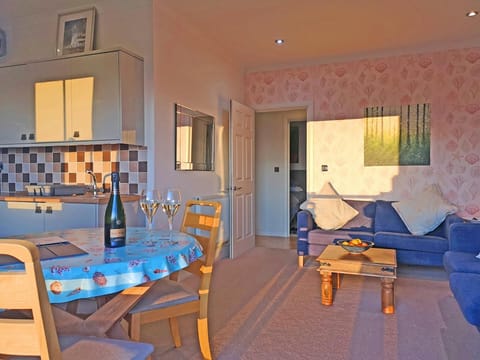 Living area with table and chairs, sofa, coffee table and kitchen