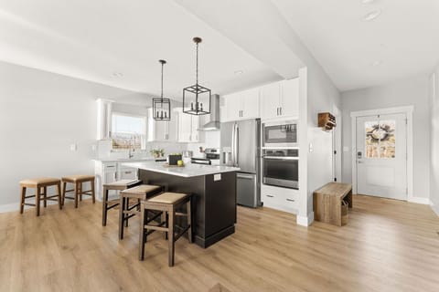 - Step into comfort with a handy bench and open-concept kitchen ready for your stay
- Island seating and stainless steel appliances make meal prep a breeze
- Light wood floors, white cabinetry, and clean design throughout