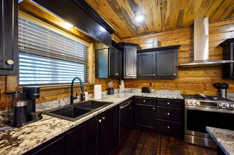 Rustic charm meets modern convenience in this cozy cabin kitchen, featuring sleek appliances and warm wood finishes—a culinary haven in the heart of Broken Bow.