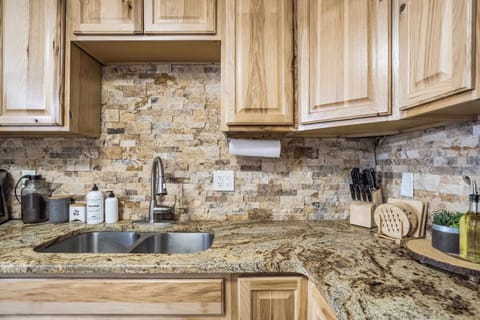 The kitchen’s elegant granite countertops and stone backsplash add a touch of warmth and charm. Fully stocked with essential cookware, utensils, and high-quality knives, this space is designed for effortless meal preparation.