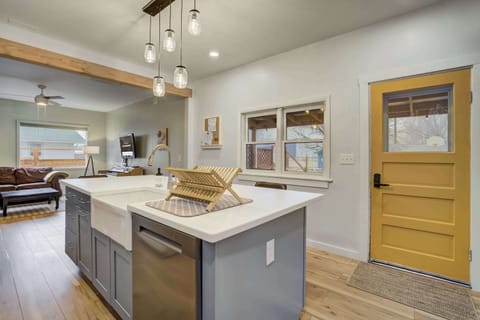 Bright and welcoming kitchen space – featuring a farmhouse sink, stylish pendant lighting, and a bold yellow door that adds a cheerful touch. The open layout seamlessly connects to the living area for easy entertaining.