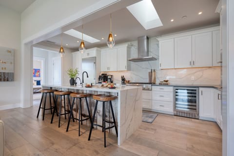 Fully equipped kitchen features Thermador appliances, Carrara-style quartz countertops, and an island with barstool seating.