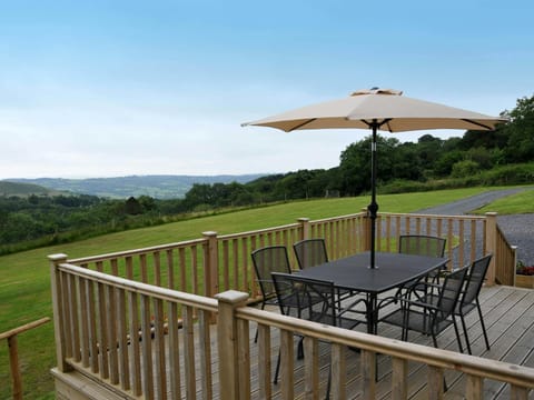 South facing raised decking with 6 chairs and umbrella. Views across fields