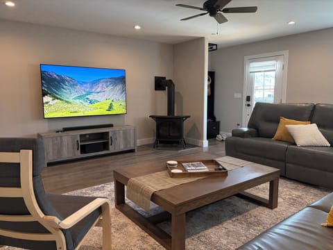 Living room with 75" smart TV and reclining leather couches.
