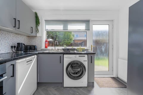 Bright and functional kitchen with modern appliances, including a washer, dishwasher, and direct access to the garden—perfect for easy living.