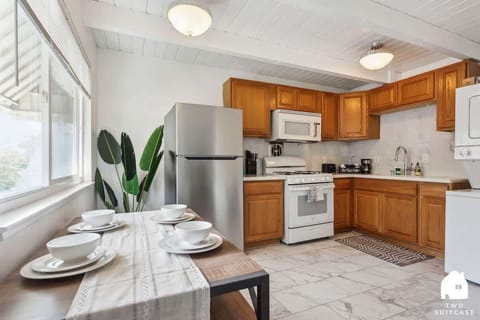 Open kitchen with wooden cabinets, full appliances, and a small dining area — great for cooking and enjoying meals at home.