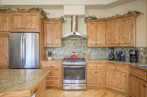 - Modern kitchen with stainless steel appliances and polished stone counters - Wooden cabinetry and mosaic backsplash add a warm mountain home style - Fully stocked cooking space offers everything for easy home dining