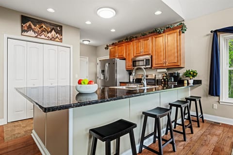 Spacious kitchen with granite countertops, bar seating, and forest views