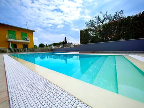 Modern communal swimming pool with step entry, perfect for relaxing and cooling off on summer days. Surrounded by a well-maintained sunbathing area and greenery, it offers a peaceful and private environment for guests of the residence.