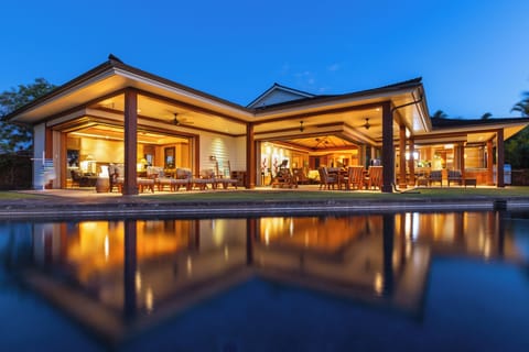 Twilight exterior of the estate home—private pool, glowing interiors, and open-concept elegance set the tone for your stay.