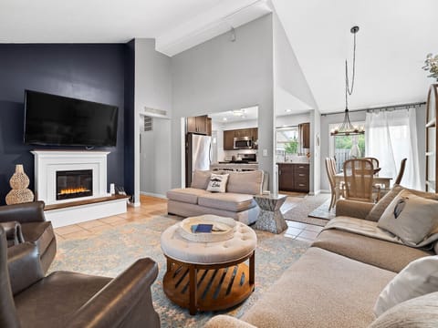 Inviting living room with fireplace and mounted TV 🔥📺. Plush seating and natural light from large windows create a perfect spot to relax. The open layout flows effortlessly from entryway to lounge 🛋️.
