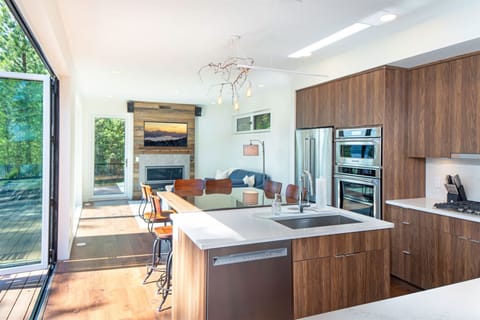 The open concept kitchen, dining & living room is framed by accordion style doors that bring the outdoors within | Main Floor