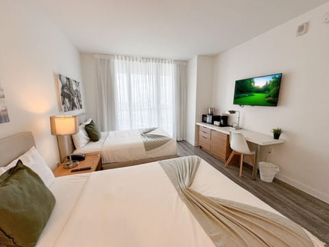 Spacious bedroom with a king-size bed, flat-screen TV, and bright natural lighting.