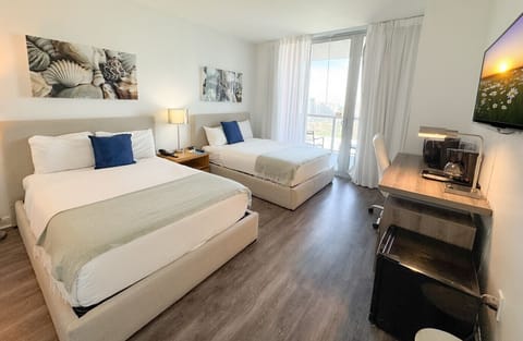 Spacious bedroom with a two beds, flat-screen TV, and bright natural lighting.