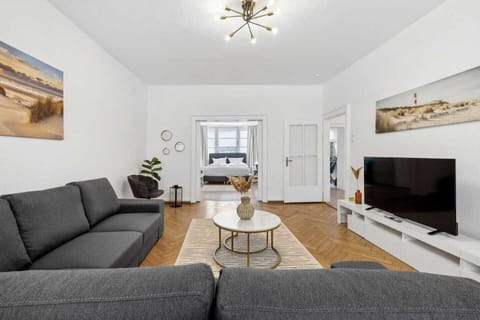 Großzügiges Wohnzimmer mit moderner Einrichtung und Blick ins Schlafzimmer.