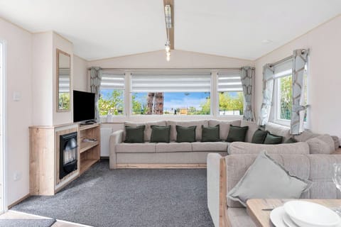 Spacious and bright living area with a large comfortable sofa, flat-screen TV, and scenic views—ideal for relaxing and socializing.