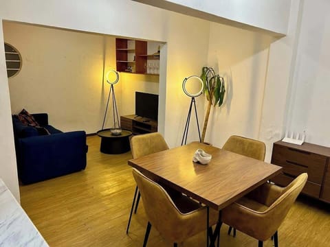 Comedor (mesa con 4 sillas, cocina integrada, planta de decoración, sala de entretenimiento al fondo)