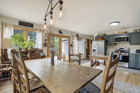 Bright and open kitchen-dining area with sage green cabinetry, stainless appliances, and a large wooden table perfect for group meals and gatherings.