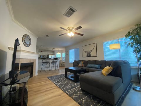 Fireplace, smart TV, soft rug, ceiling fan. The living room is set