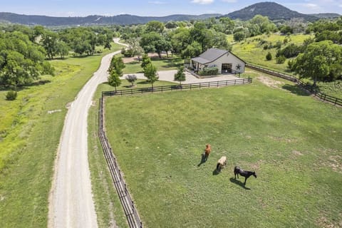 Escape to this serene countryside retreat, offering expansive green pastures where horses graze peacefully, a long private driveway, and stunning views of rolling hills and lush trees