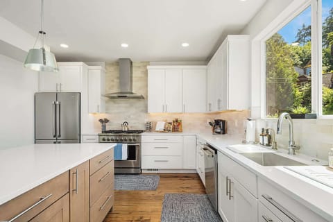 Sunlit modern kitchen with stainless appliances and coffee nook.