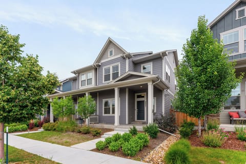 Charming two-story gray house with porch, garden, greenery, and peaceful vibe