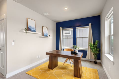 Cozy Modern home office with wooden desk, comfy chair, brigt rug, and plants