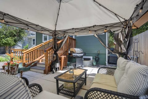 Relax in the shared patio lounge complete with cozy seating, a BBQ grill, and string lighting for peaceful evenings outdoors.