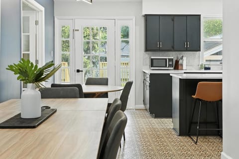 This open dining and kitchen space blends style and functionality, featuring sleek cabinetry, a microwave, and bar seating. Natural light pours in through French doors, making it the perfect spot for meals, snacks, or coffee breaks.