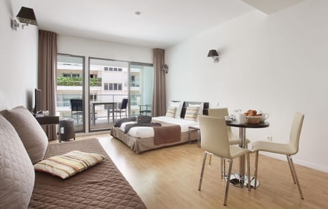 Step into a sunny studio with seating and dining space, opening onto a private balcony for fresh-air moments.