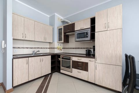 A modern kitchen with light-colored cabinets, an oven, and an induction stove.