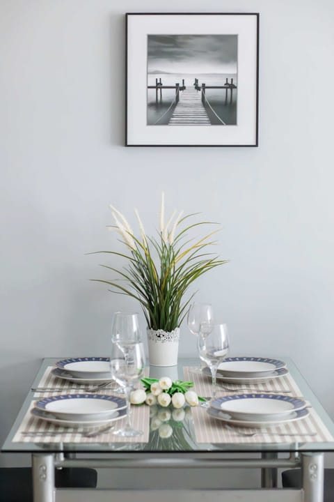 Close-up of the dining table with kitchenware. Above the table is a poster.