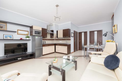 A spacious, well-lit living room with a dining area in the background, offering a cozy sofa and decorative elements. The neutral tones create a warm and inviting ambiance.