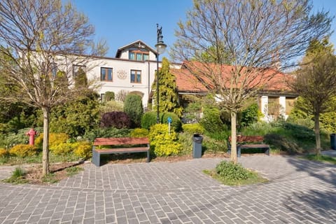 A lush garden with cobblestone paths and shaded benches.