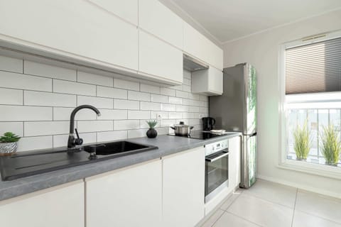 A stylish kitchen corner featuring a black backsplash, decorative plants, and a wooden countertop. The contrast between the black and white elements creates a sleek look.