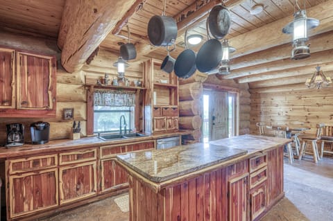 Rustic log cabin kitchen with rich wood cabinetry, granite countertops, and charming hanging lantern lights