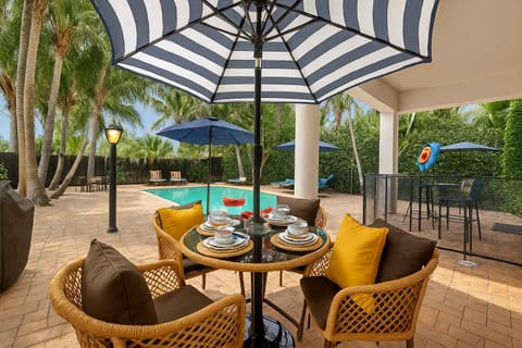 Dine poolside in style under shaded umbrellas. This outdoor space is perfect for family meals, morning coffee, or evening drinks in your private Fort Lauderdale retreat. #VacationRental #FtLauderdaleHome #PrivatePool