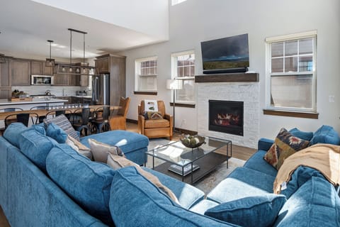 - Spacious open plan layout connects the cozy living room with the kitchen - Blue sectional and fireplace offer comfort for relaxing or socializing - Large windows, clean design, and rustic accents tie it all together