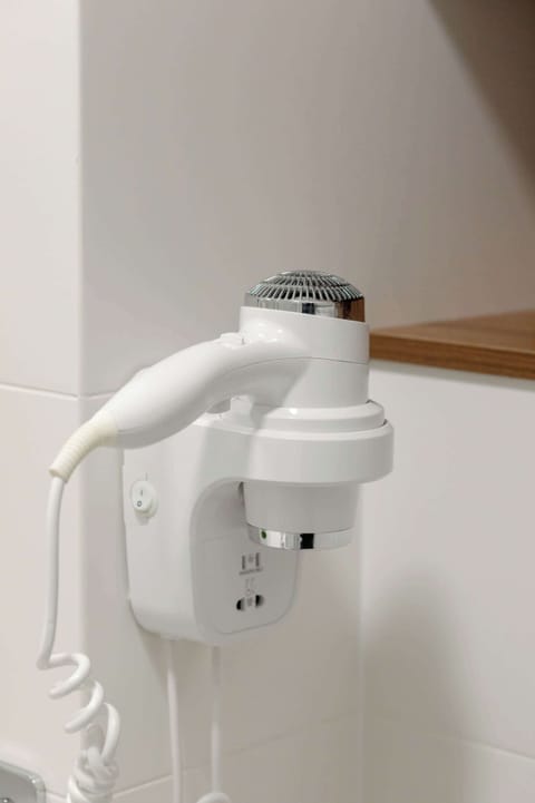 A white hair dryer mounted on the bathroom wall provides convenience and functionality, ideal for daily use during your stay.