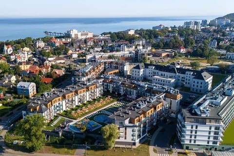 Another aerial view showcasing a vibrant coastal town with residential buildings and green surroundings.
