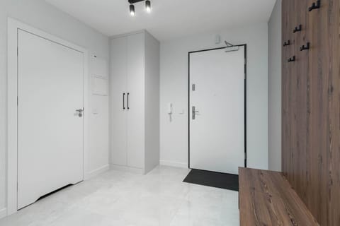 The entrance to the apartment, a bright and welcoming hallway with a white door and a coat rack.