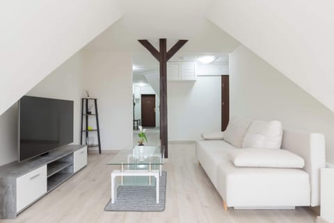 A modern living room with a white corner sofa, a glass coffee table and a large TV mounted on a low RTV cabinet just in time for relaxation. 