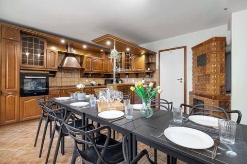 A dining room connected to a kitchen, with a large table and chairs. A welcoming space for group dining.