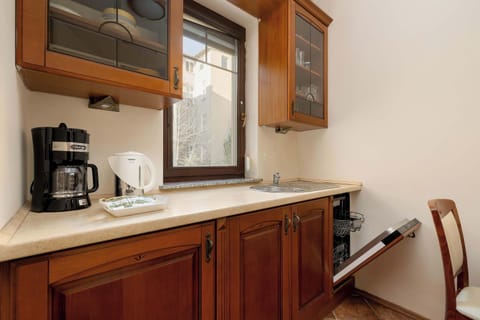 There is a coffee machine and an electric kettle on the bright countertop. There is a built-in dishwasher in the cupboard.
